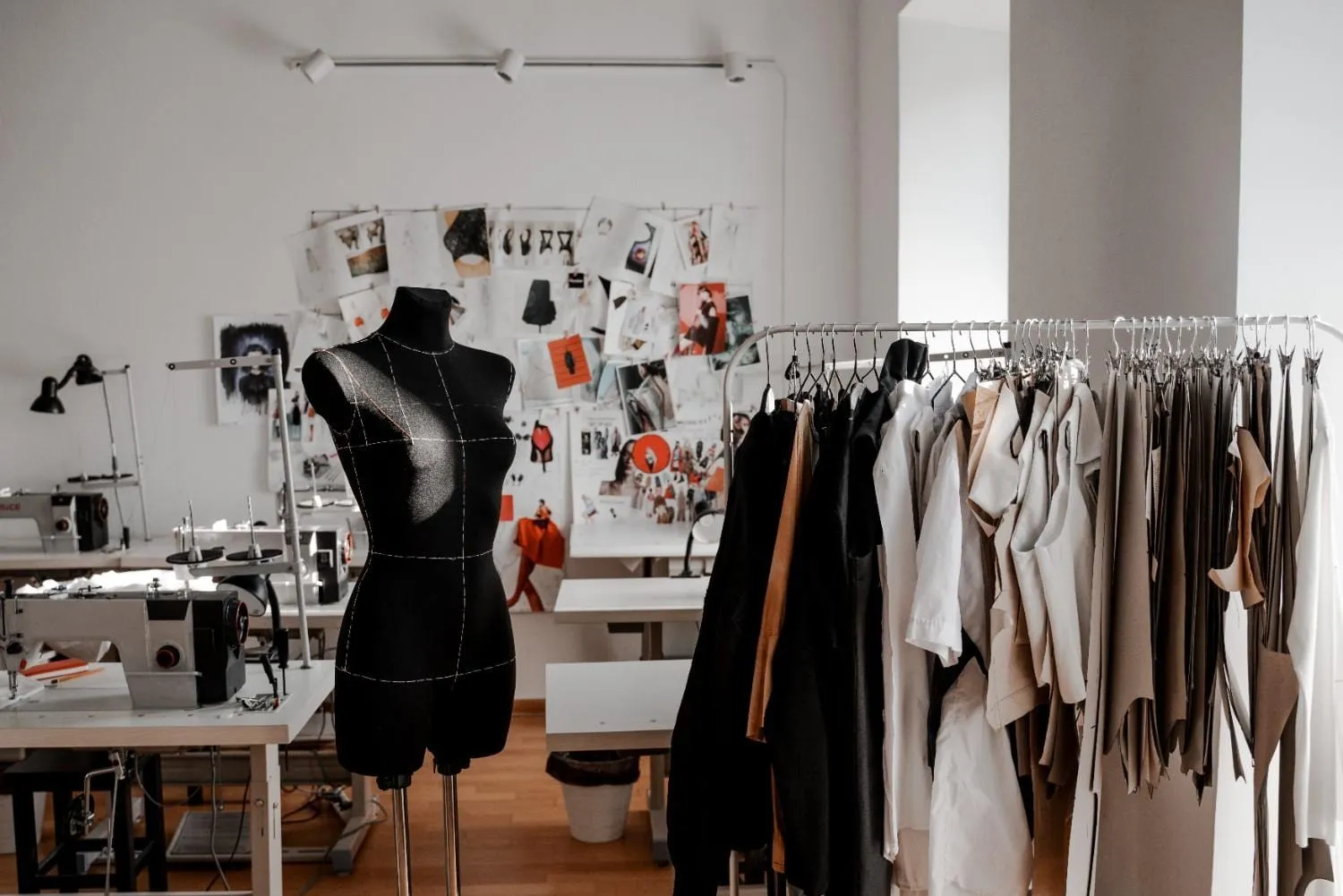 Apparel design studio with a dress form, sewing machines and a rack of garments, showing the manufacturer's workshop